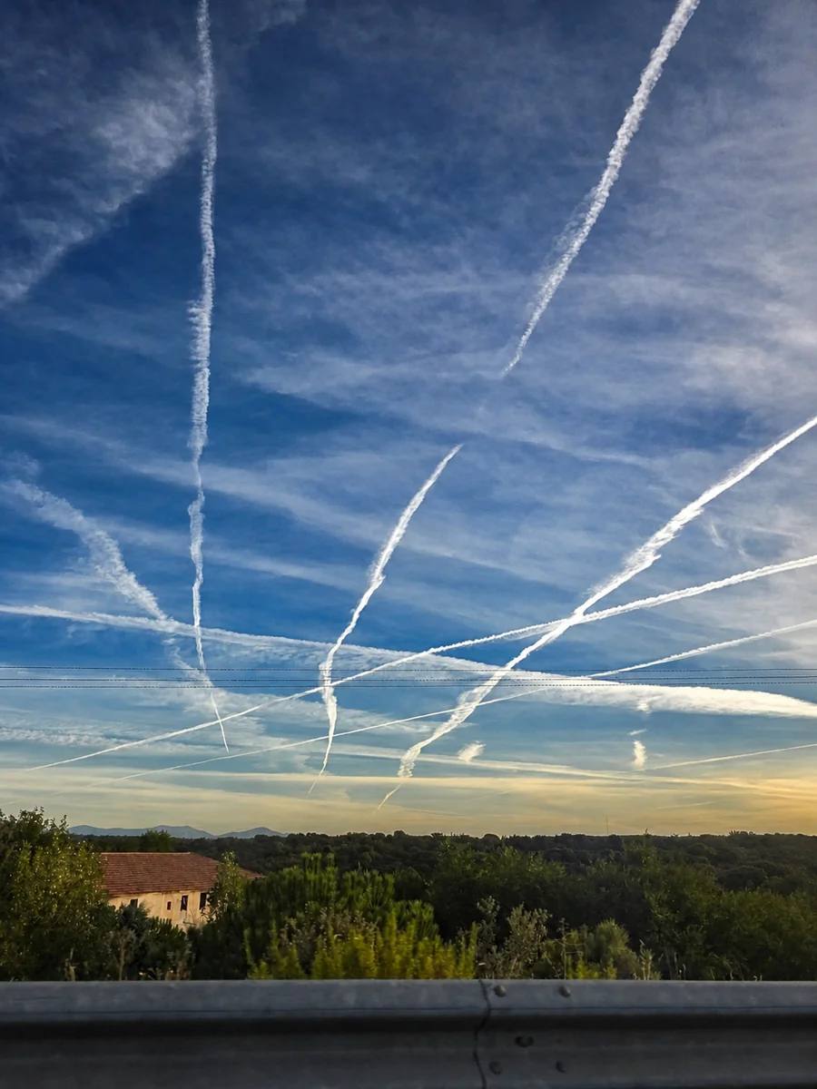 Céu em Madri: as linhas chamam atenção, mas o horizonte, as casas e até o guard-rail ajudam a lembrar que a foto era uma cena real, não um céu inventado.