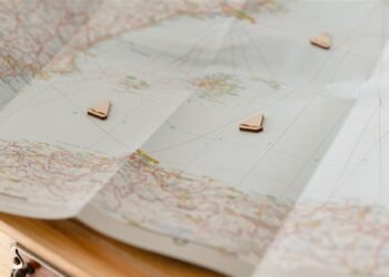 Mapa dobrado sobre uma mesa com pequenos marcadores em forma de barco indicando pontos de um roteiro de viagem.