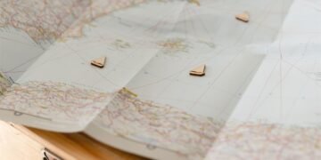 Mapa dobrado sobre uma mesa com pequenos marcadores em forma de barco indicando pontos de um roteiro de viagem.