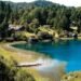 Vista de Llao Llao em Bariloche, com lago azul, vegetação e casas entre as montanhas.