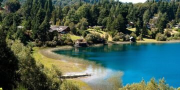 Vista de Llao Llao em Bariloche, com lago azul, vegeta��o e casas entre as montanhas.