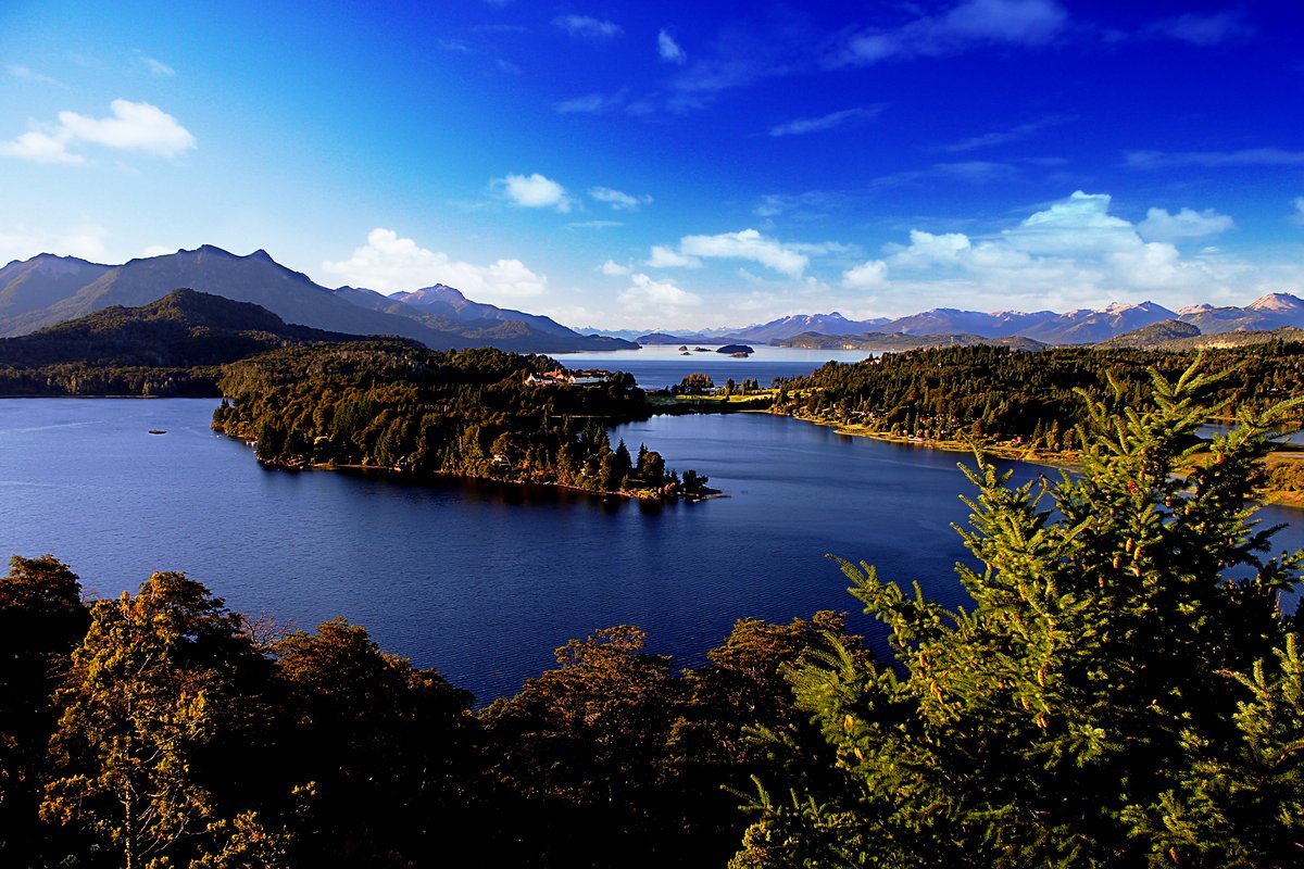 Vista do lago Nahuel Huapi em Bariloche, com água azul e montanhas ao fundo.