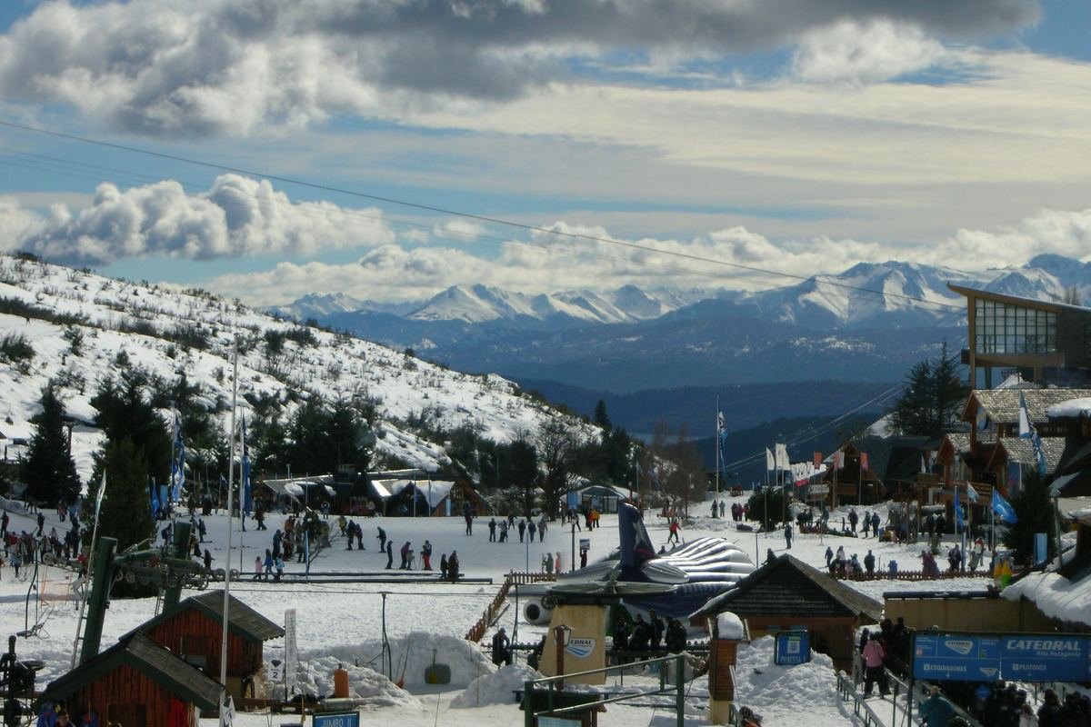 Base do Cerro Catedral no inverno, com pistas de esqui, construções e as montanhas nevadas ao fundo.