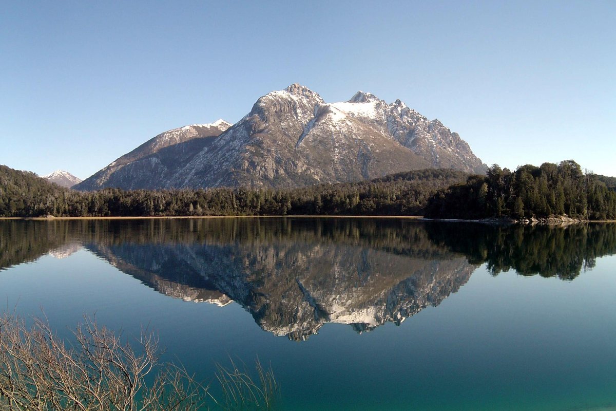 Paisagem do Circuito Chico em Bariloche, com lago, montanhas e mata ao redor.