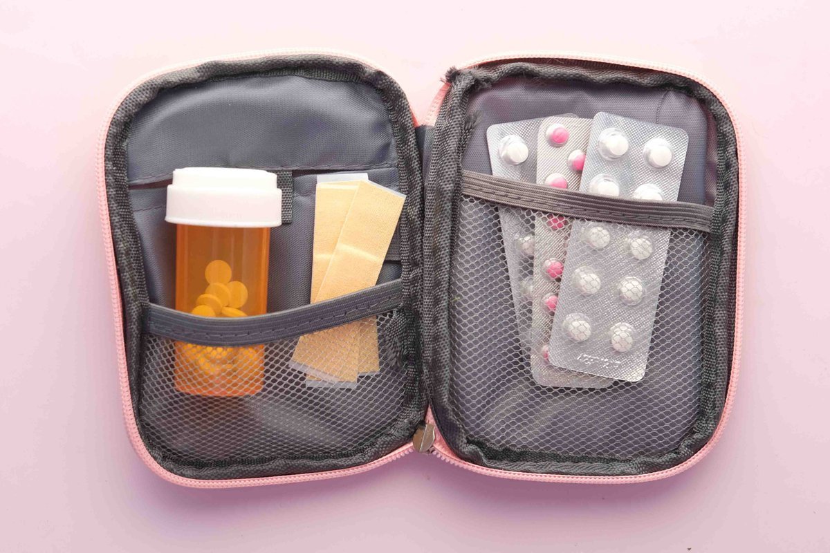 Kit de primeiros socorros aberto, com remédios e band-aids.