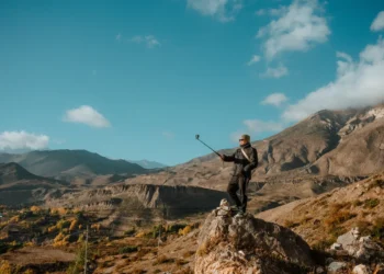 Viajante tirando selfie com bastao em paisagem de montanha