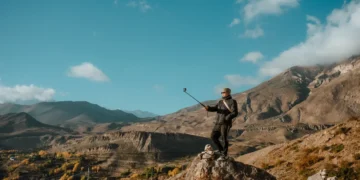 Viajante tirando selfie com bastao em paisagem de montanha