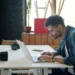 Fotógrafo edita imagens em um laptop, com uma câmera sobre a mesa.