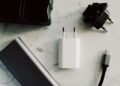 Power bank, carregador, adaptador de tomada e cabo USB-C sobre uma superfície clara.