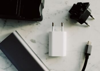 Power bank, carregador, adaptador de tomada e cabo USB-C sobre uma superfície clara.