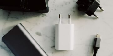 Power bank, carregador, adaptador de tomada e cabo USB-C sobre uma superfície clara.