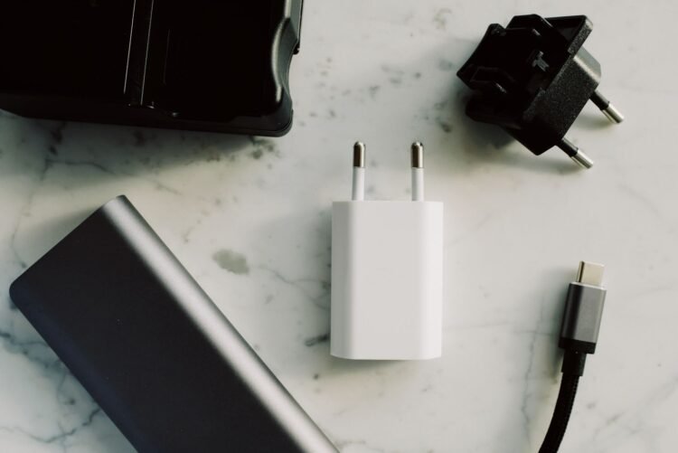 Power bank, carregador, adaptador de tomada e cabo USB-C sobre uma superfície clara.